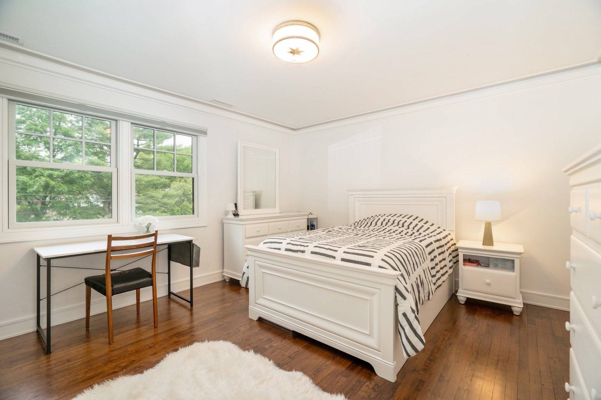 Light-filled second bedroom with desk and queen bed