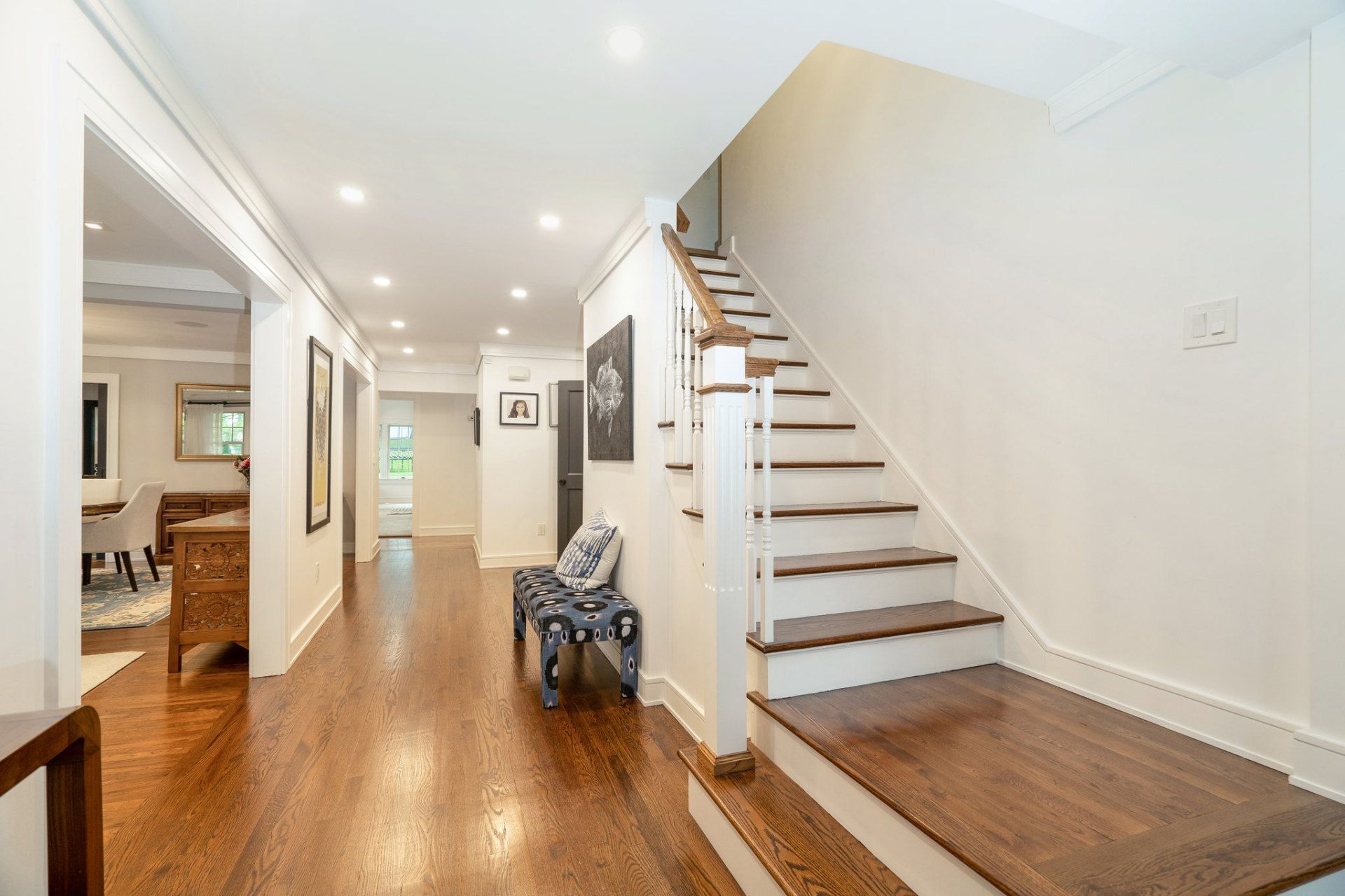 Bright entry hallway with hardwood floors and staircase