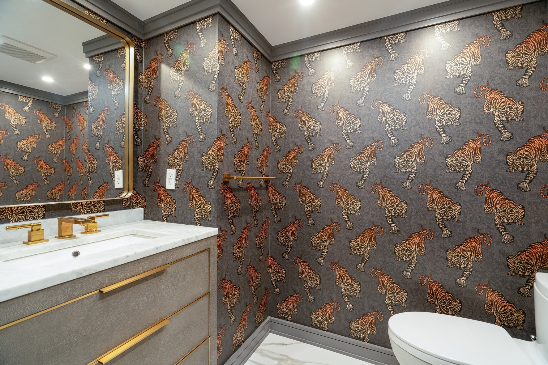 Designer powder room with bold tiger wallpaper and brass fixtures