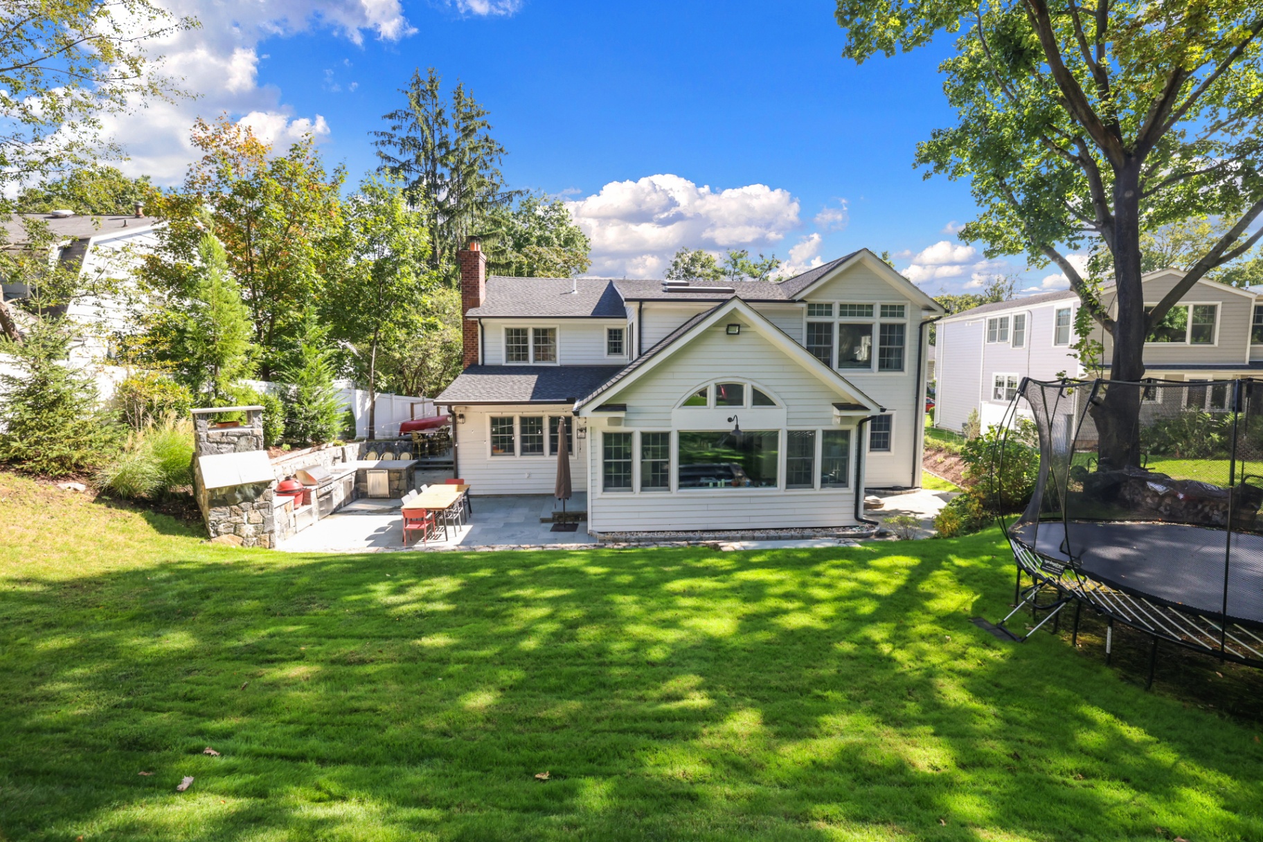 Expanded rear view with patio, outdoor kitchen, and lush lawn
